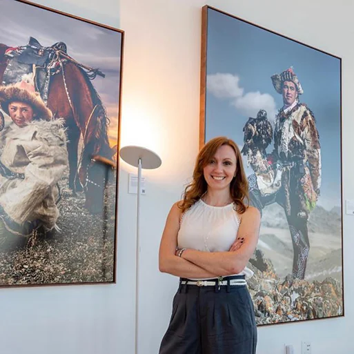 Photographer Claire Thomas with large prints displayed at her Eagle Hunters exhibition